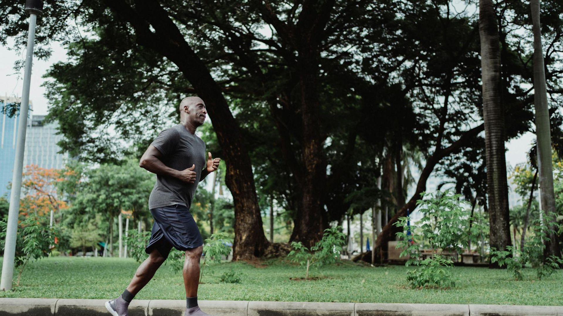 Active man jogging during sunrise in a modern city park